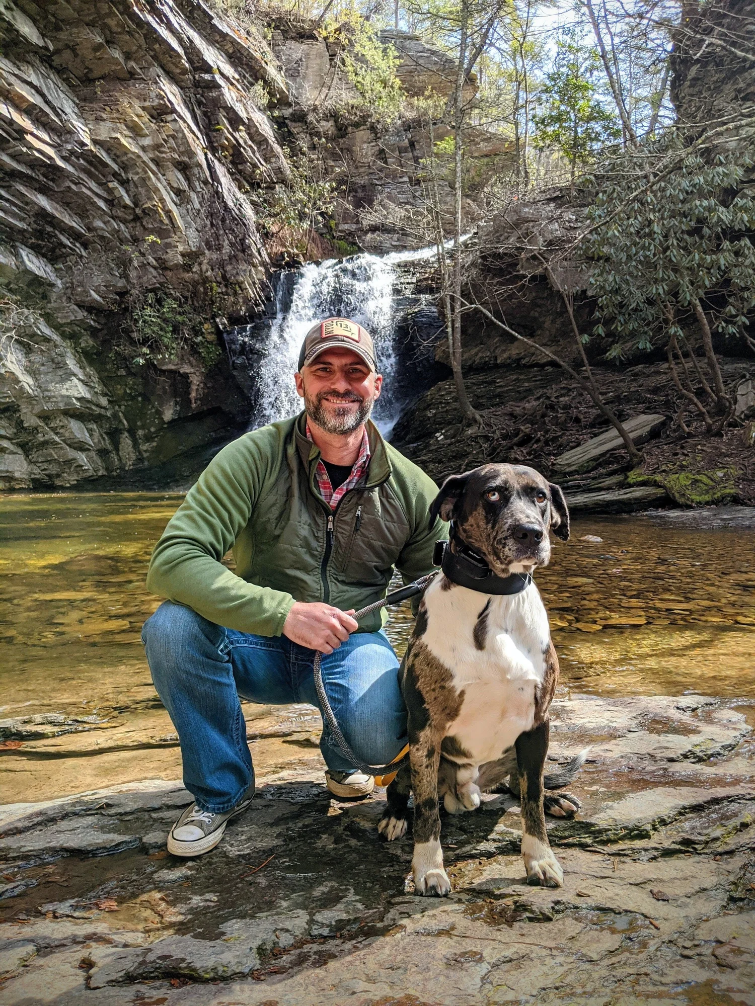 Jeremy Davis with a dog beside a waterfall